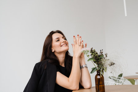 Cheerful girl is making wishes and enjoy lifestyle in white office. Young business woman is smiling in cafeの写真素材