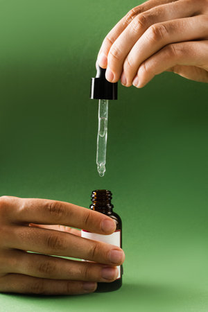 Pipette with Cannabidiol CBD oil in hand. CBD oil from the Cannabis plant to help reduce pain, anxiety, and sleep disordersの写真素材