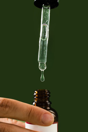 Pipette with Cannabidiol CBD oil in hand close-up. CBD oil from the Cannabis plant to help reduce pain, anxiety, and sleep disordersの写真素材
