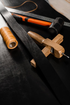 Genuine leather belt, thread, hammer and ruler. Tools of craftsman for belts creation. Equipment for...