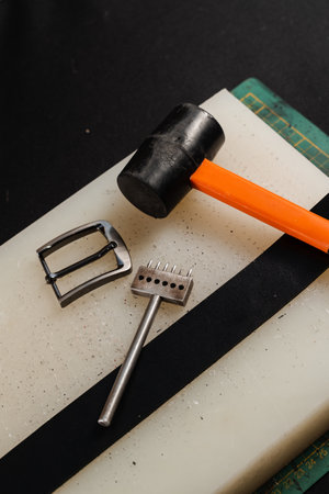 Genuine leather belt, buckle, hammer and line punch. Tools of craftsman for belts creation....