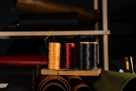 Needle and spools of thread and rolls of natural leather in craftsman workshop. Handmade genuine leather production in the factoryの写真素材