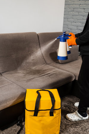 Spraying detergent on couch for dry cleaning using extractor machine. Process of dry cleaning for removing stains and dirt from couch at home. Professional cleaning serviceの写真素材