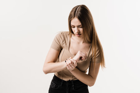Wrist injury of girl hand on white background. Traumatology. Attractive girl with pain and bruise in...