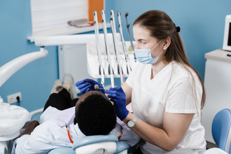 Dentist examines teeth of african man for treatment of toothache. Pain in teeth. Consultation with dentist in dentistryの写真素材