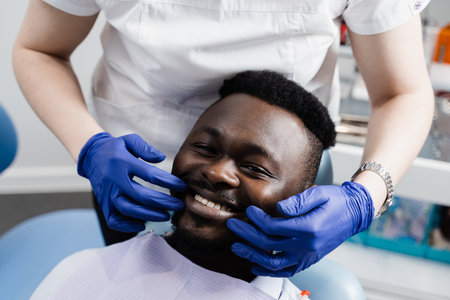 Dentist examines teeth of african man for treatment of toothache. Pain in teeth. Consultation with dentist in dentistryの写真素材