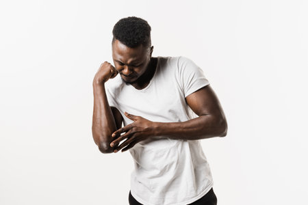 Elbow injury causing pain, swelling, stiffness, and limited movement. Fractures, dislocations, sprains, and tennis elbow. Elbow injury of african american man isolated on white backgroundの写真素材