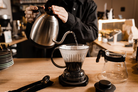 Pouring hot water over roasted and ground coffee beans contained in paper filter. Clever coffee dripper with pour over filter coffee alternative brewing methodの写真素材