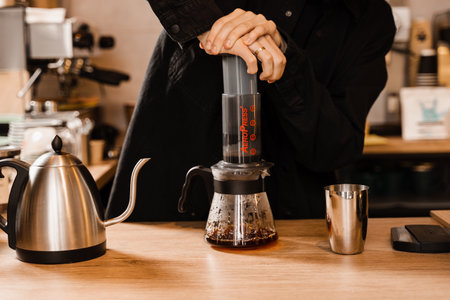 Aeropress coffee. Barista is pushing aeropress for pouring coffee drops trought aeropress to pot. Alternative scandinavian coffee brewing methodの写真素材