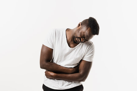 Ulcer or gastritis stomach ache. Sick african american man hold abdomen because it hurts. Pancreatitis disease of pancreas becomes inflamedの写真素材