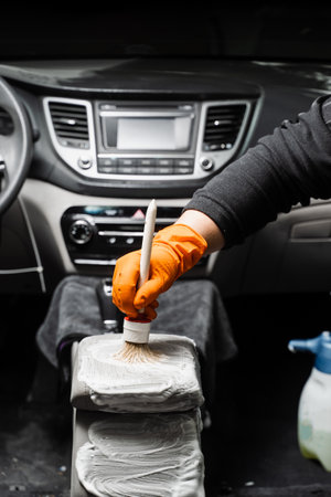 Dry cleaning with brush of dashboard in car. Auto detailing service. Cleaning individual elements of...