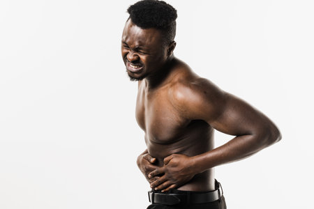 Muscular african american man with pelvic inflammatory disease on white background. PID infection of one or more of the upper reproductive organs, including the uterus, fallopian tubes and ovariesの写真素材