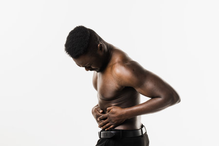 Muscular african american man with pelvic inflammatory disease on white background. PID infection of one or more of the upper reproductive organs, including the uterus, fallopian tubes and ovariesの写真素材
