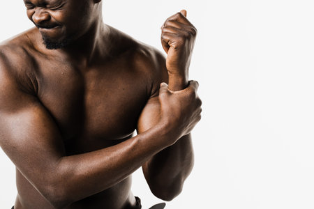 Wrist injury of muscular african american man on white background. Traumatology. African american man with pain and bruise in his arm due to an accidentの写真素材