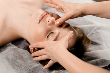 Masseur is making facial beauty treatments for attractive female model. Neck and face massage in the spa. Relaxationの写真素材