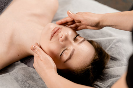 Masseur is making facial beauty treatments for attractive female model. Neck and face massage in the spa. Relaxationの写真素材