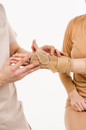 Wrist external orthosis to reduce pathological mobility of wrist joints. Traumatologist puts external wrist bandage on girls hand to recover from injuries and reduce risk of new injuriesの写真素材