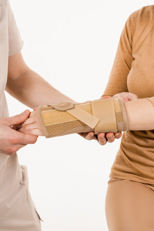 Wrist external orthosis to reduce pathological mobility of wrist joints. Traumatologist puts external wrist bandage on girls hand to recover from injuries and reduce risk of new injuriesの写真素材