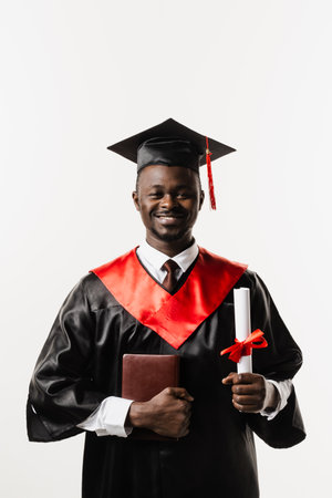 Graduate african man graduated from university and got master degree. Graduation. Happy african man smiling and holding diploma with honors in his hands on white backgroundの写真素材