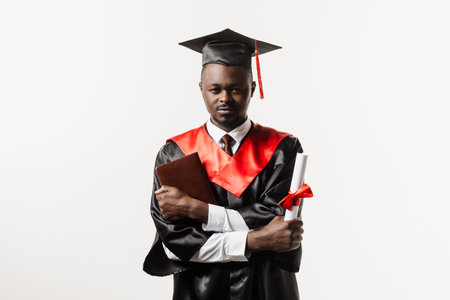 Confident african student with diploma in graduation robe and cap ready to finish college. Future leader of science. Academician african man in black gown smilingの写真素材