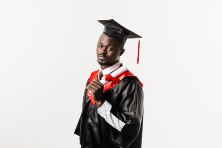 Confident african student with diploma in graduation robe and cap ready to finish college. Future leader of science. Academician african man in black gown smilingの写真素材