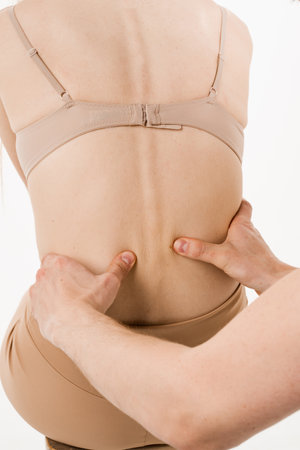 Examination of scaleosis and hernia of girl on white background. Orthopedist traumatologist examines...