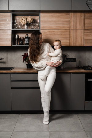 Happy mother with her daughter on the kitchen. Mon and her kid spend time at home togetherの写真素材