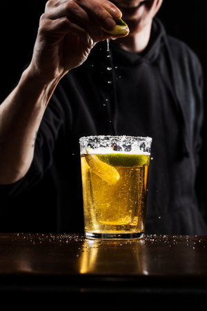 Bartender squeezes lime and sprinkles juice over the Death of Mexican alcoholic cocktail with shot of tequila and lime with beer at the barの写真素材