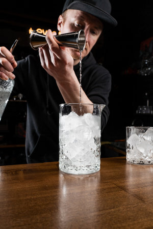 Bartender prepares traditional Negroni cocktail at the bar. Bartender mixes gin, and sweet vermouth...