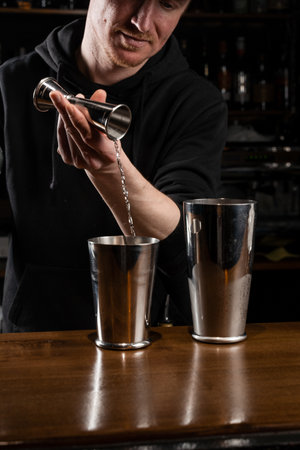 Bartender prepares classical Clover club alcoholic cocktail at the bar. Bartender mixes egg white, lemon, dry vermouth and gin to prepare the Clover club cocktailの写真素材