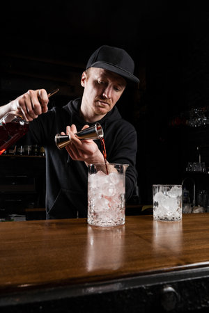 Bartender prepares traditional Negroni cocktail at the bar. Bartender mixes gin, and sweet vermouth to prepare the Negroni alcoholic cocktailの写真素材