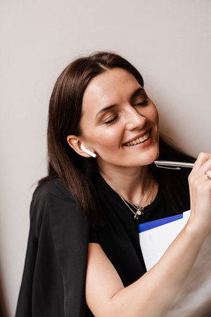 Cheerful girl with book in cafe. Concentrated English teacher writes notes before online lesson via video communication. Distance learningの写真素材