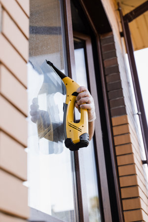 Cleaning window using portable vacuum windows cleaner. Washer of cleaning service cleans outside of...