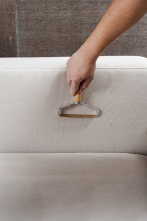 Cleaning couch using portable lint shaver remover from cat and dog hair. Manual sofa scraper...