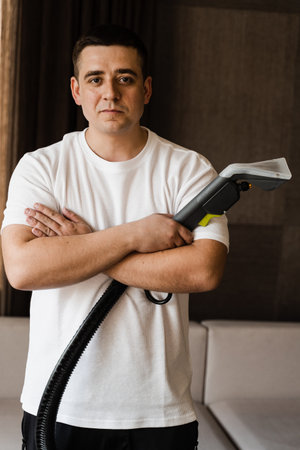 Portrait of professional cleaner with washing vacuum cleaner extractor machine in hands for cleaning and removing dirt and dust from upholstered textile couchの写真素材