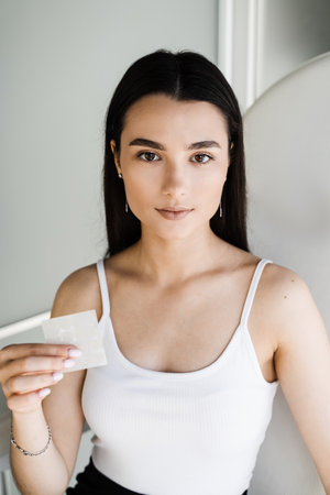 Girl with acne stick round acne patch in hands. Using acne patches for treatment of pimple and...
