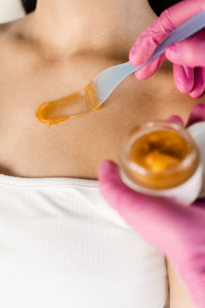 Beautician applies gold lifting mask on body to stimulate natural processes of skin renewal and restore elasticityの写真素材