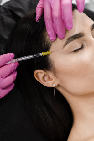 Cosmetologist injecting facial biorevitalization for moisturizing effect. Close-up facial biorevitalization for increasing skin tone, reducing wrinkles, and strengthening oval of the faceの写真素材