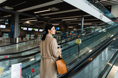 Traveler going to boarding gate to start 2024 trip abroad. Woman in coat with handbag moving up on...