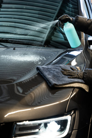 Polishing car body using microfiber cloth. Professional car valeting. Wiping vehicle after applying...