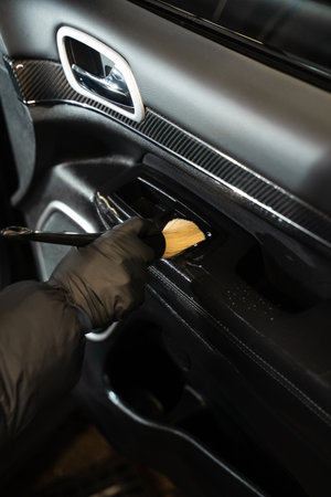 Cleaning car door using soft brush. Professional car detailing. Removing dirt and stains from car interiorの写真素材