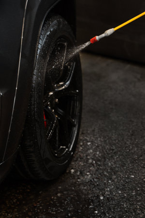 Washing wheel in the self-service car wash. Cleaning automobile with high pressure water jet. Presoak application before using high-pressure water jet to clean the carの写真素材