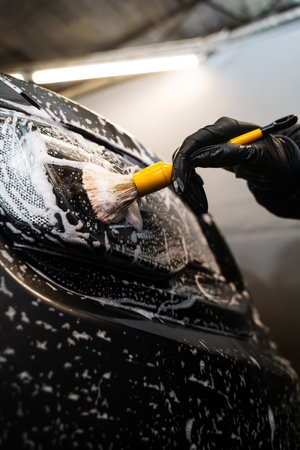 Manual cleaning with soap at self care car wash. Cleaning headlights with foam and soft brush....
