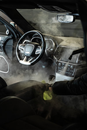 Process of steam cleaning gearbox of leather car interior. Removing spots from vehicle salon. Sanitizing and disinfecting of textile salonの写真素材