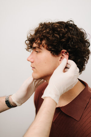 Otoplasty for changing the shape, position or size of the ears. Surgeon doctor examines ear of male...