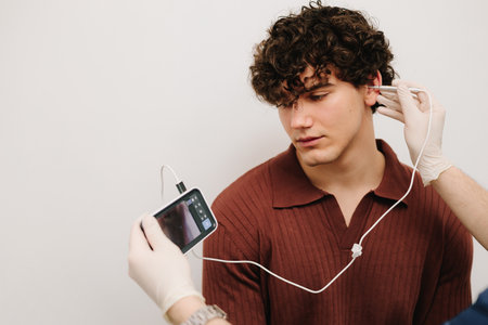Process of examining patients ear with digital otoscope. Patient is looking at screen of digital...
