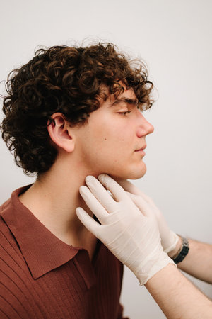 ENT doctor palpates the neck to determine inflammation of the lymph nodes of man. ENT doctor...