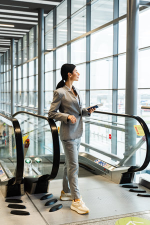Traveler standing with documents near escalator in airport terminal and waiting for flight departure...
