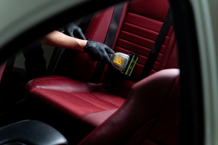 Removing dust from auto seats using special vacuum cleaner. Detailing car backseat with the help of...