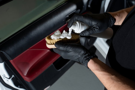 Hand splashes flacon of cleaning solution in order to wipe the car door panel. Detailing process....
